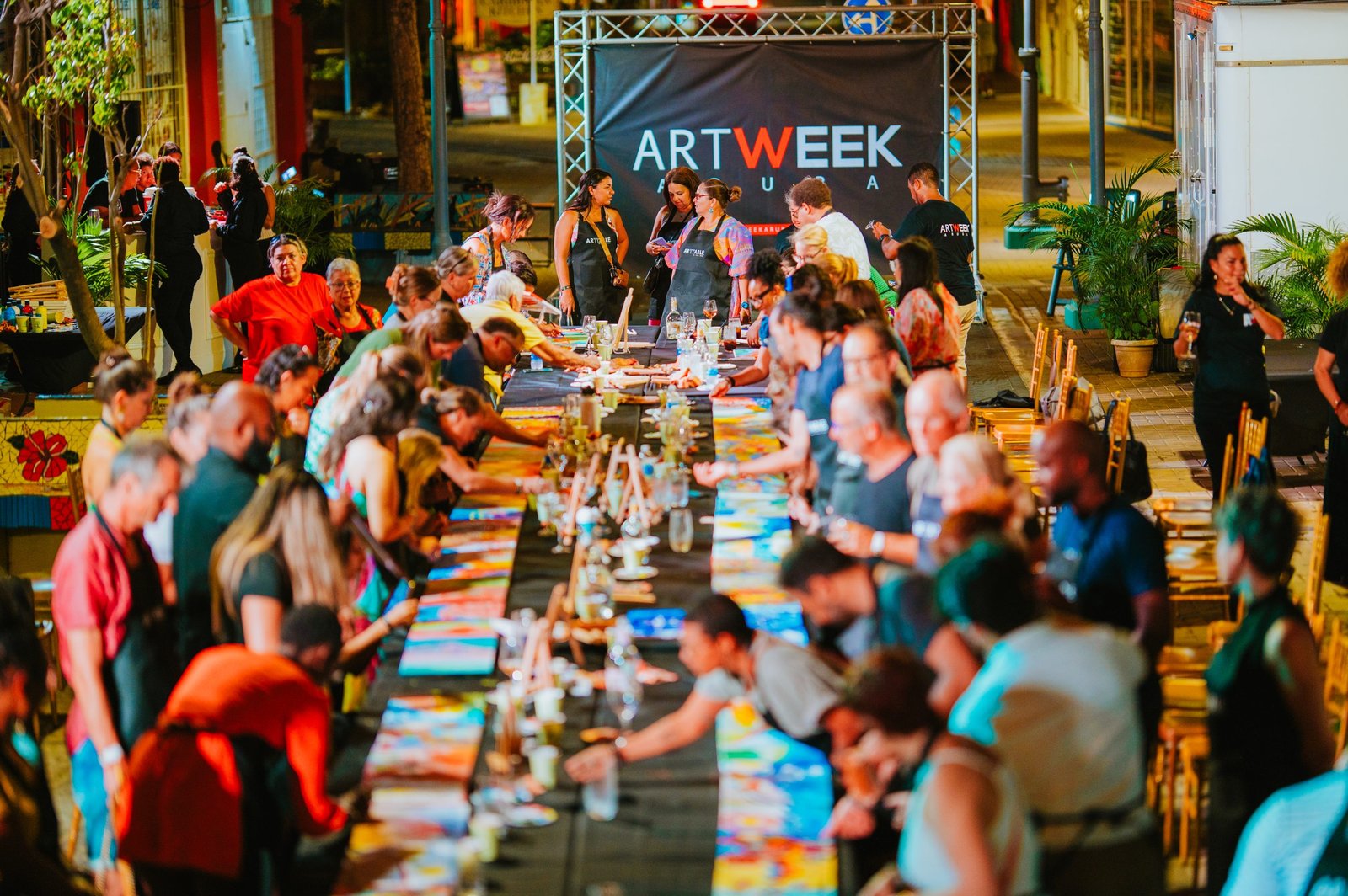 Guests painting at one long table at ArtTable, Art Week Aruba, San Nicolas