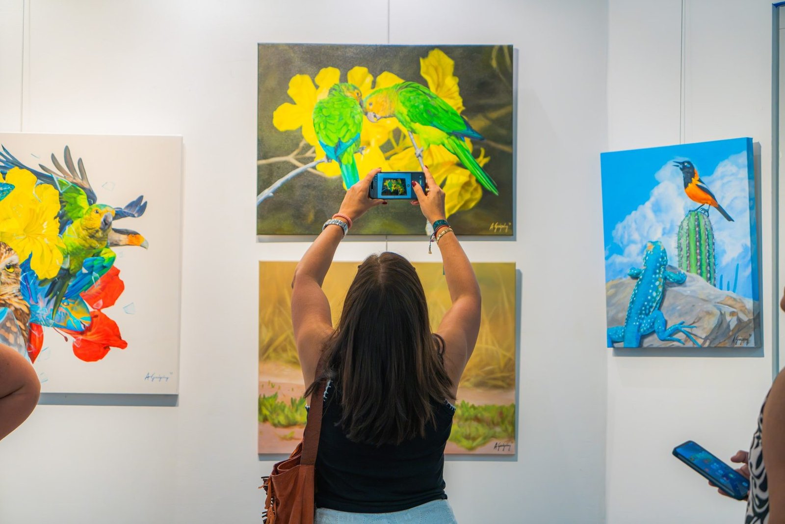 A visitor photographs a painting at Aruba Art Fair 2026