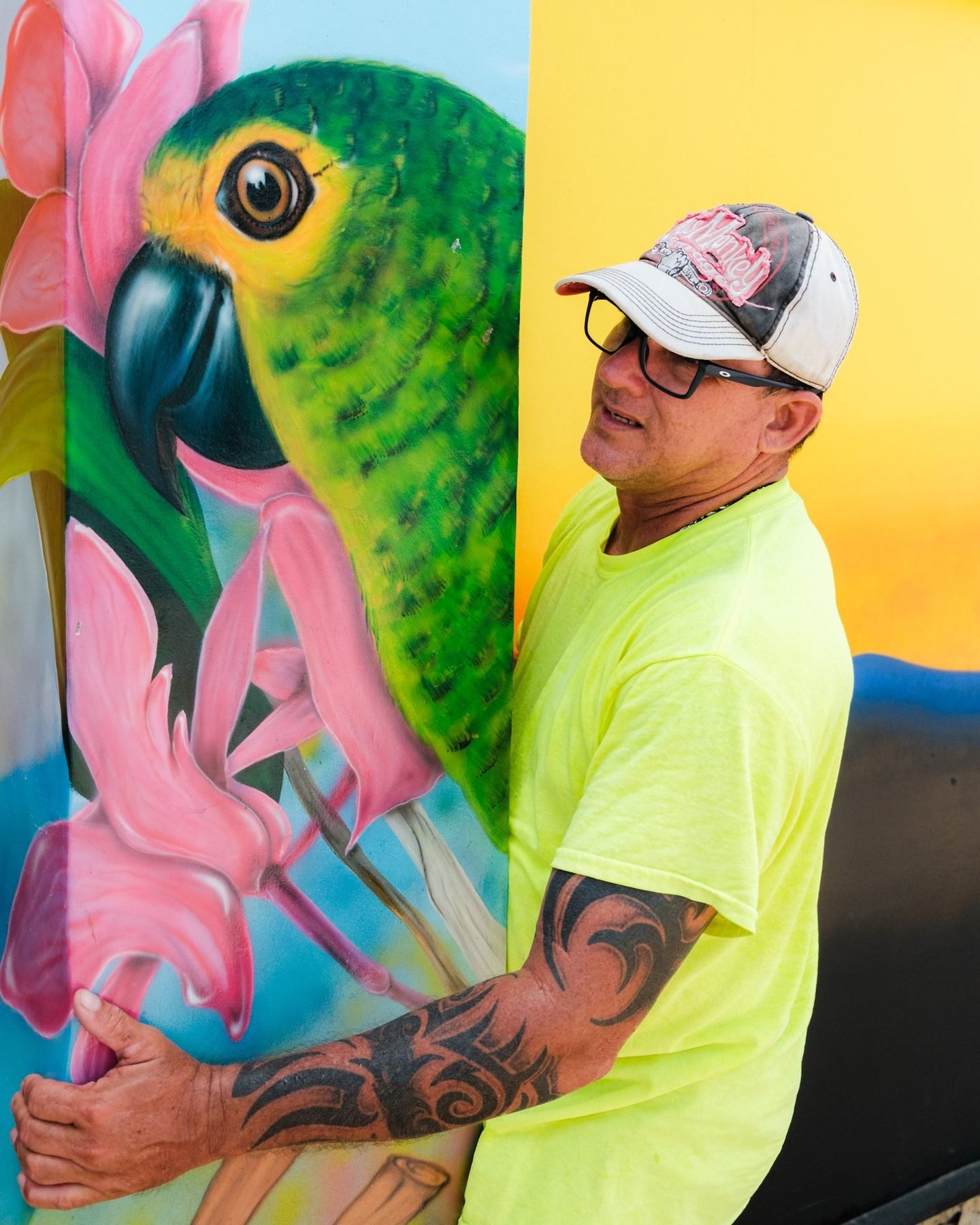 A muralist next to his parrot mural